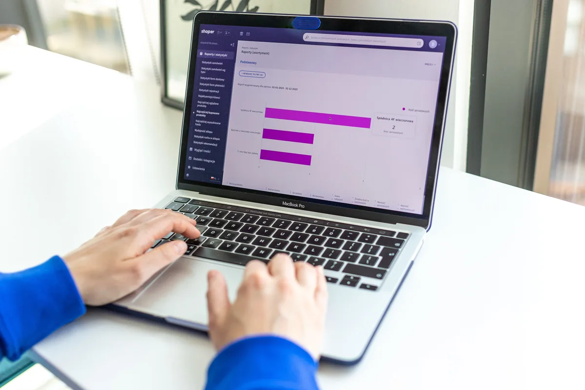 Hands typing on a laptop showing an ecommerce store’s reports and statistics dashboard