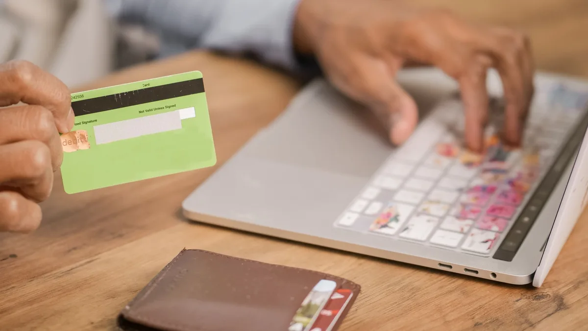 Person completing a card payment on a laptop, representing the moment before a shopper becomes a cart abandoner
