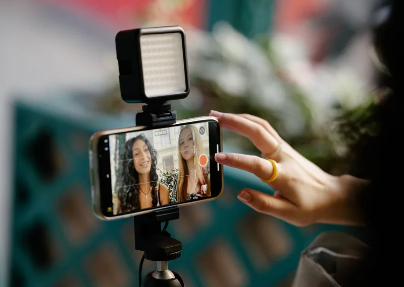 Two creators filming short-form product video content with a smartphone and LED light for social media marketing
