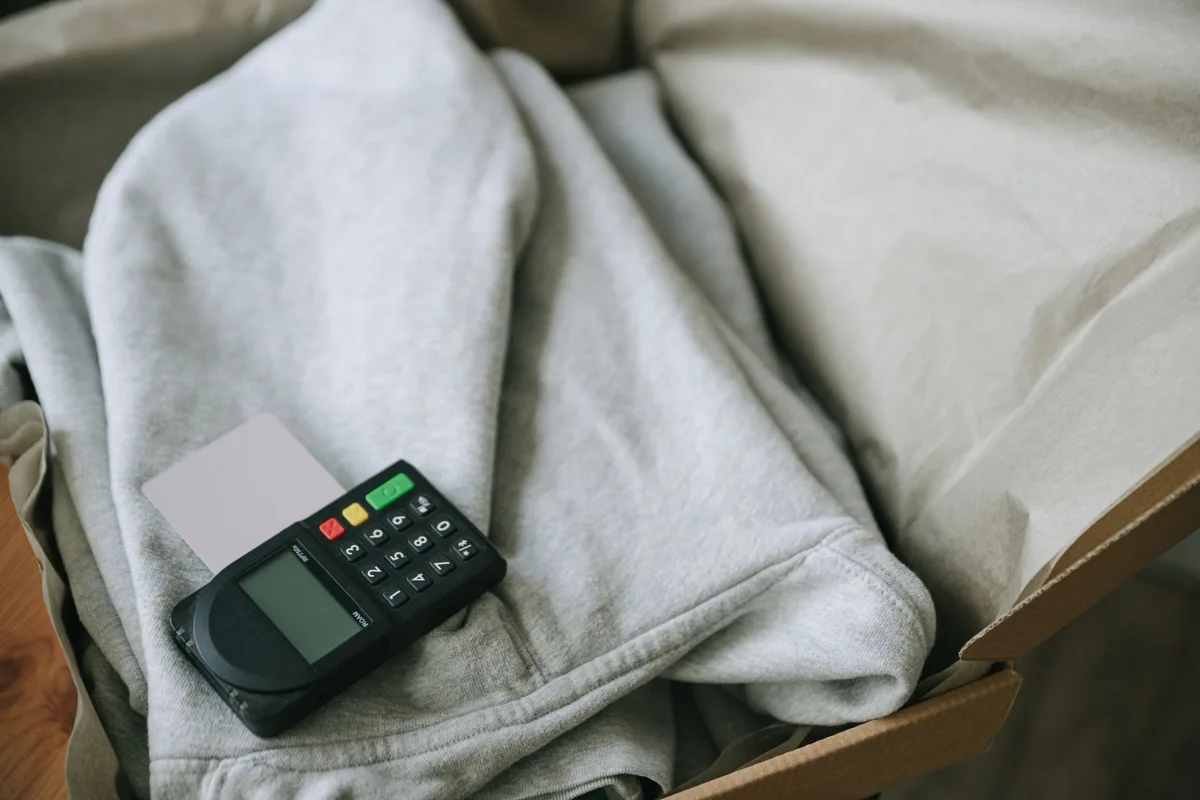Payment terminal and card placed beside packaged ecommerce orders, representing checkout and conversion