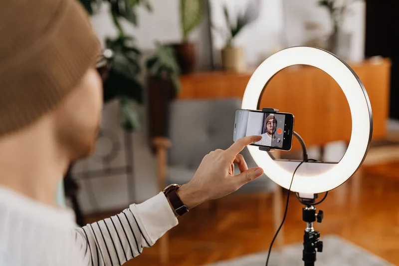 Content creator recording video content with a smartphone and ring light in a home studio setup