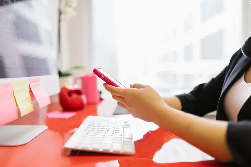 Professional checking mobile phone at modern office workstation