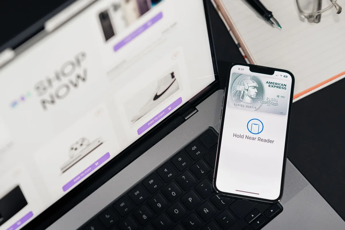 Smartphone payment app next to a laptop showing an online store during checkout