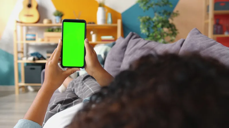 Person browsing a shopping app on a smartphone while relaxing at home