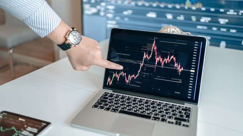 Hand pointing at a sales growth chart displayed on a laptop screen