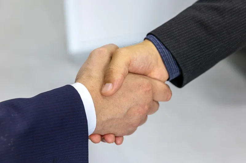 Two businesspeople shaking hands, representing a brand and affiliate partner agreement