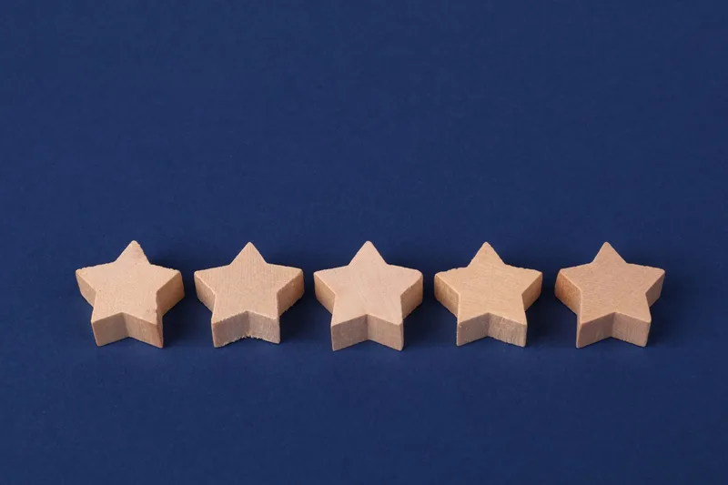Five wooden stars arranged in a row on a blue background, representing a five-star customer review rating