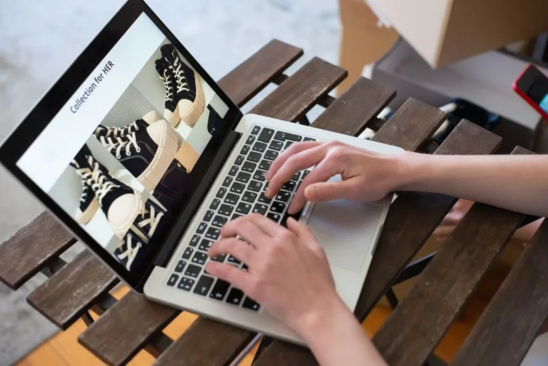 Hands typing on a laptop showing an online store’s product collection page