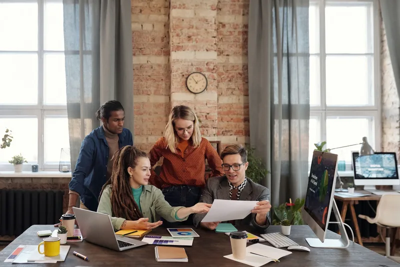Team of marketing professionals reviewing affiliate campaign performance data and strategy plans in a business office